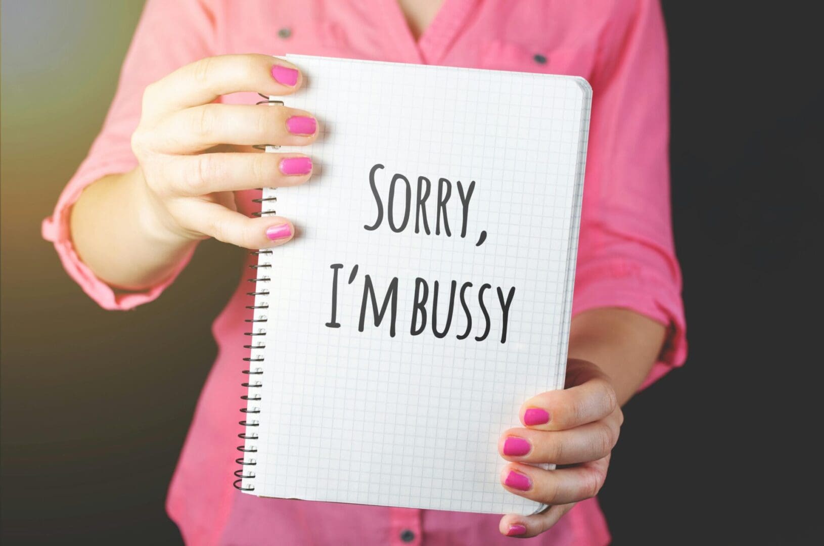 Person holding notebook with 'SORRY, I'M BUSSY' message.