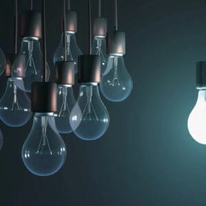 A group of unlit bulbs with one glowing bulb on the side.