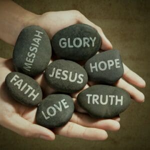 Hands holding stones with words like Faith, Love, and Truth.
