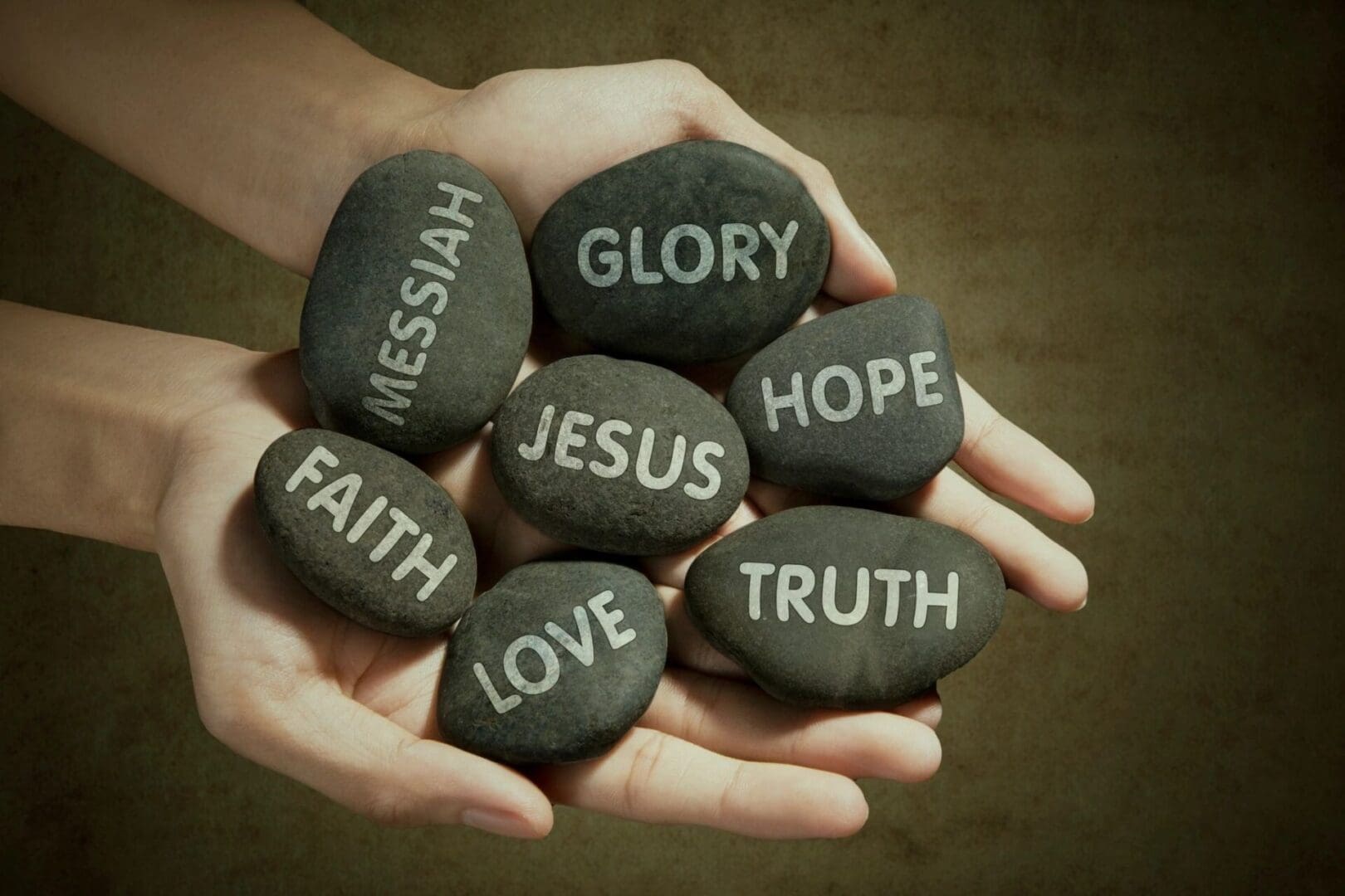 Hands holding stones with words like Faith, Love, and Truth.