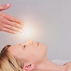 A person receiving energy healing with hands above their head.