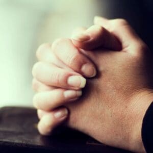 Hands clasped together in a gesture of prayer or contemplation.