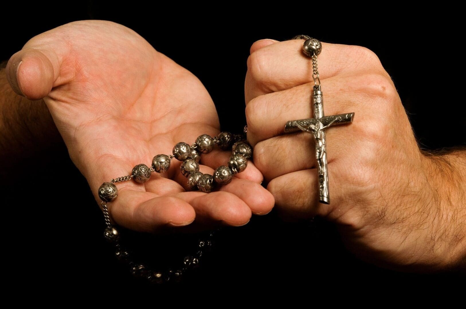 Hands holding a rosary with a crucifix.