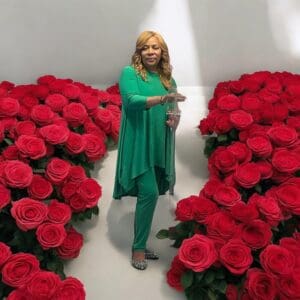 Person standing between two large heart-shaped arrangements of red roses.