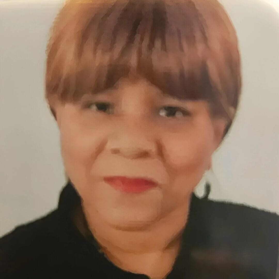 Portrait of a smiling woman with short brown hair and gold earrings.