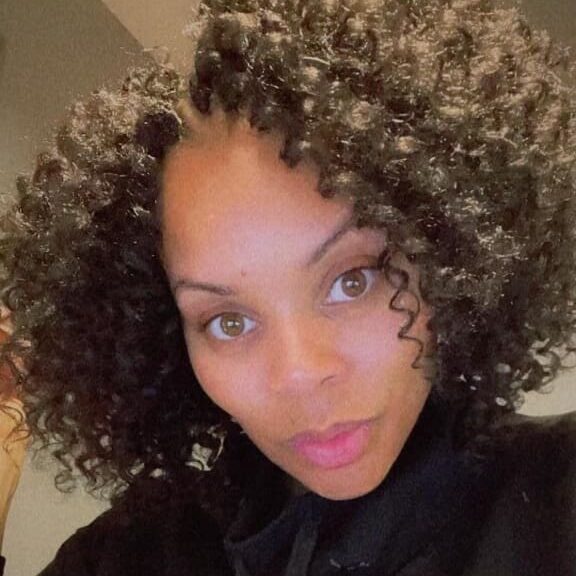 Close-up of a woman with curly hair and a soft smile.